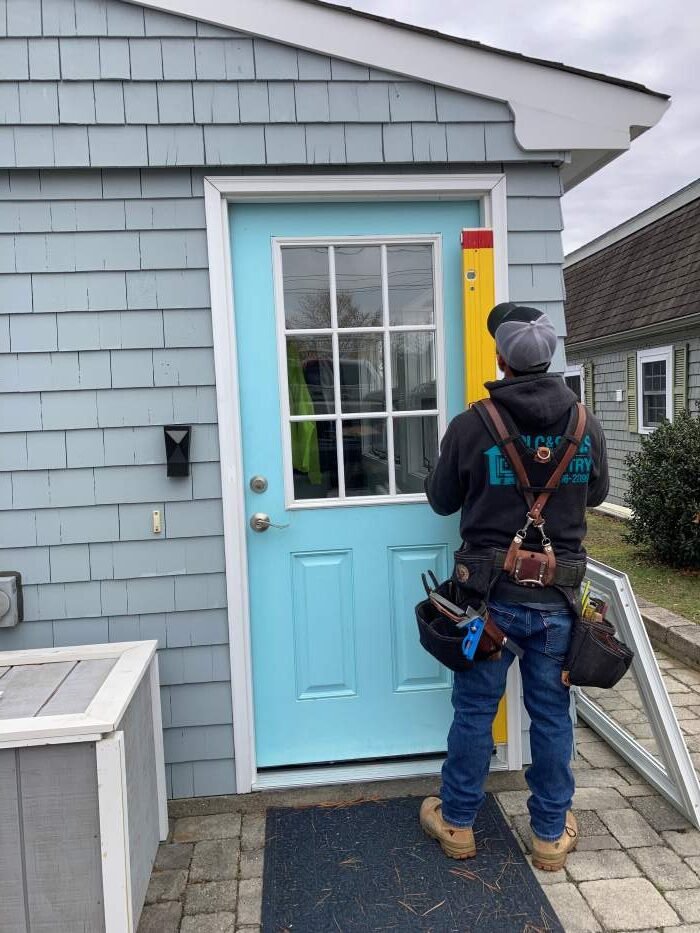 CLC And Sons Carpentry owner using a level to ensure a professional door installation in Raynham, MA.